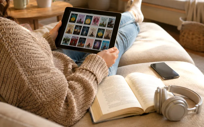 A reader browsing Story Metro on a tablet beside an open book and headphones